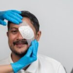 Smiling middle aged man receiving protective eye patch from healthcare worker wearing gloves after surgery, concept of medical treatment, injury recovery, hospital care, vision protection patient.